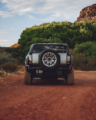 A black truck driving down a dirt road