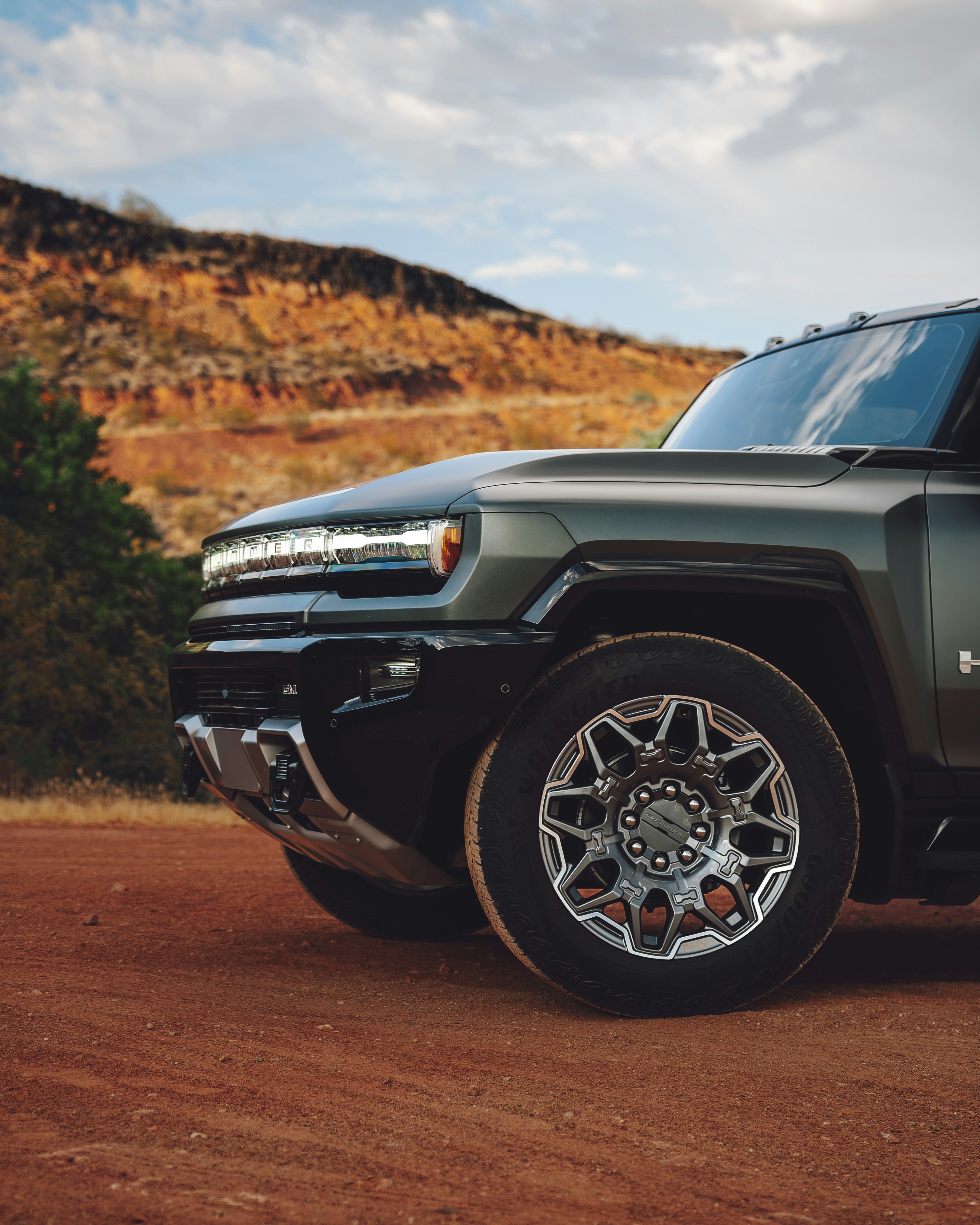 A green truck parked on the side of a dirt road