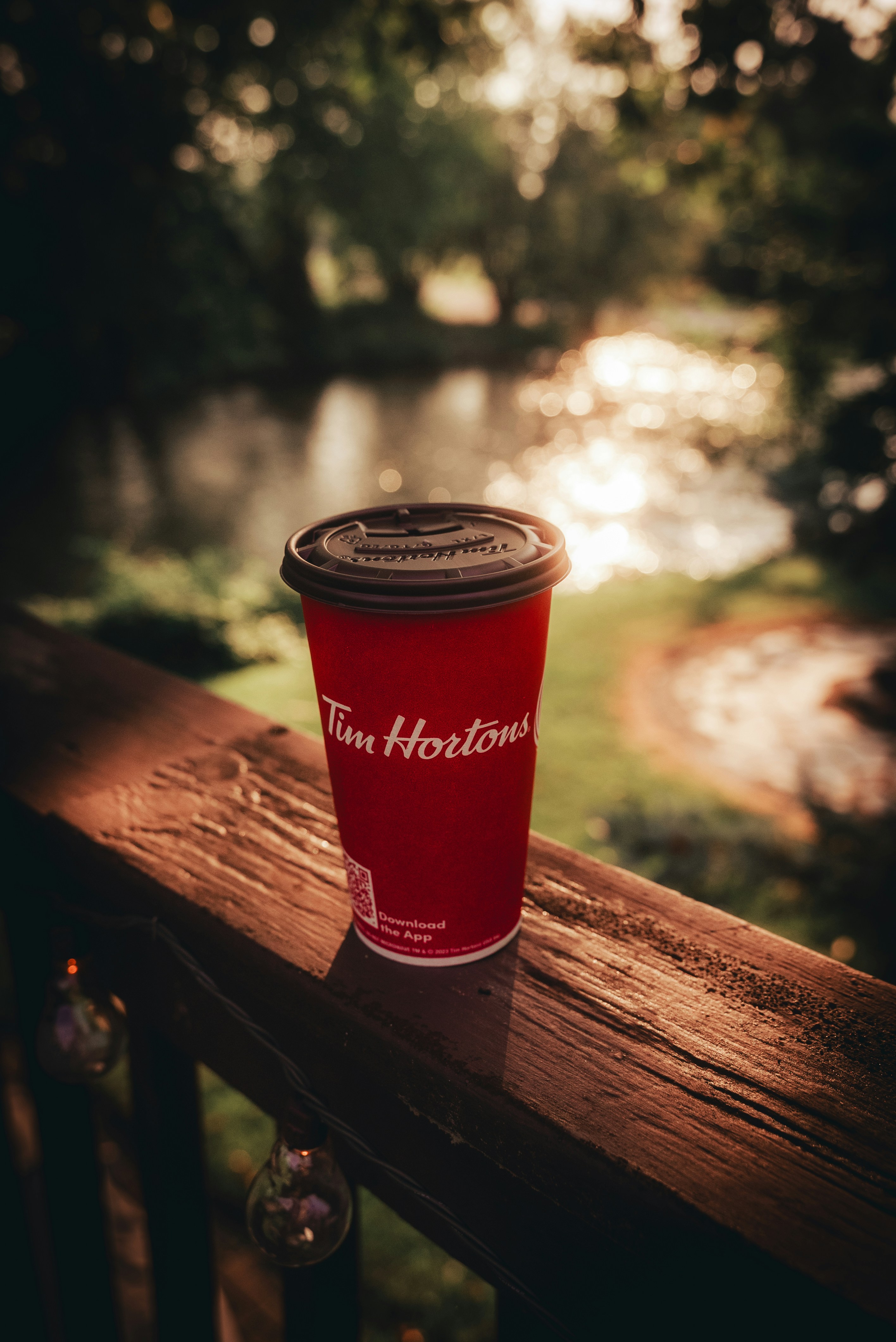 A red cup sitting on top of a wooden railing