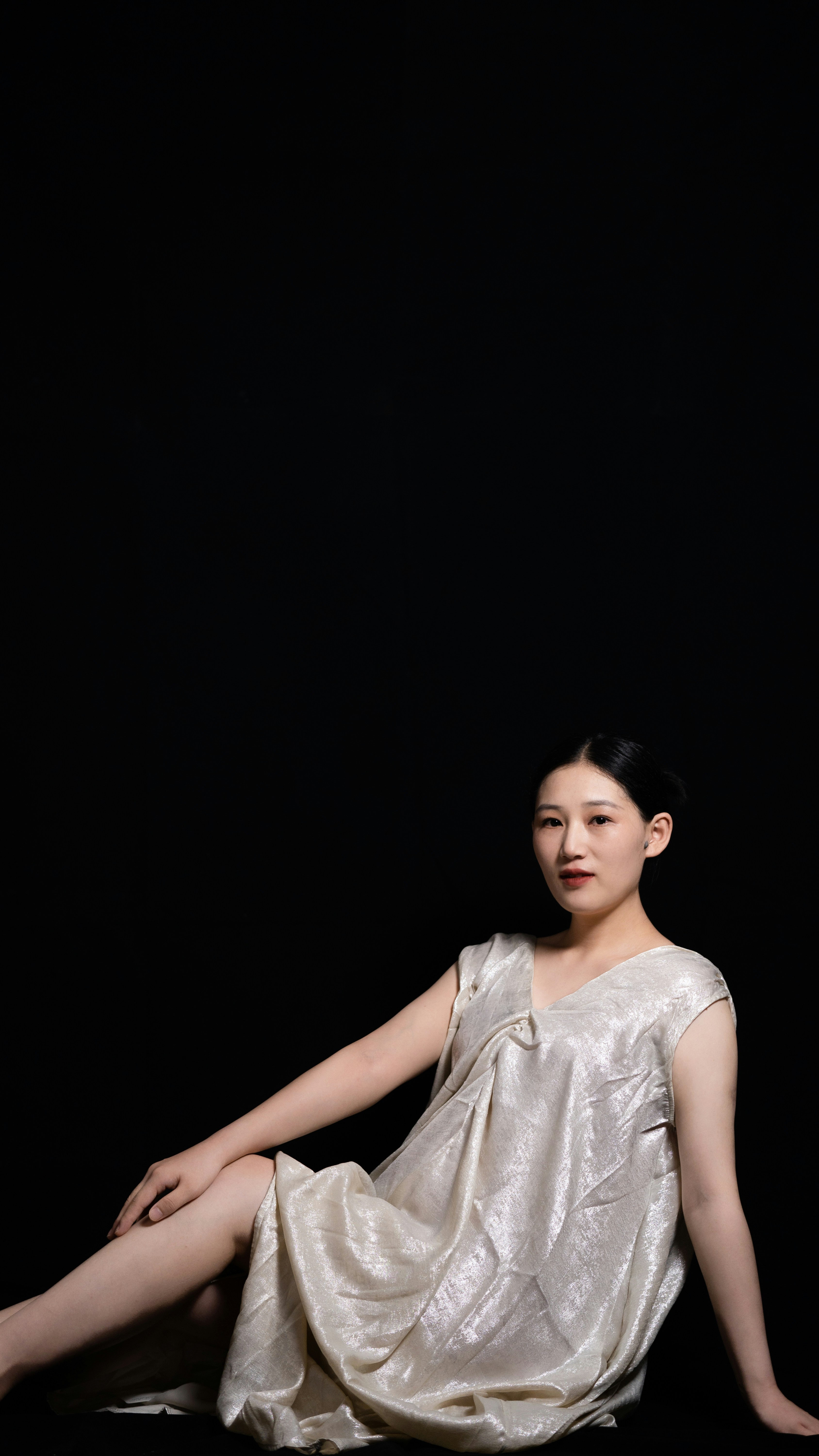 A woman sitting on the ground in a white dress