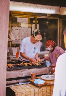 A group of people standing around a kitchen preparing food
