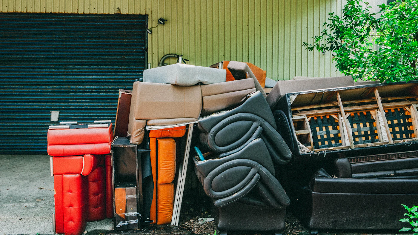 Pile of old couches and furniture outside a garage