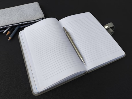 A notebook with a pen and pencils next to it