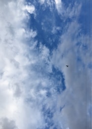 A plane flying through a cloudy blue sky