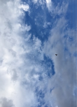 A plane flying through a cloudy blue sky