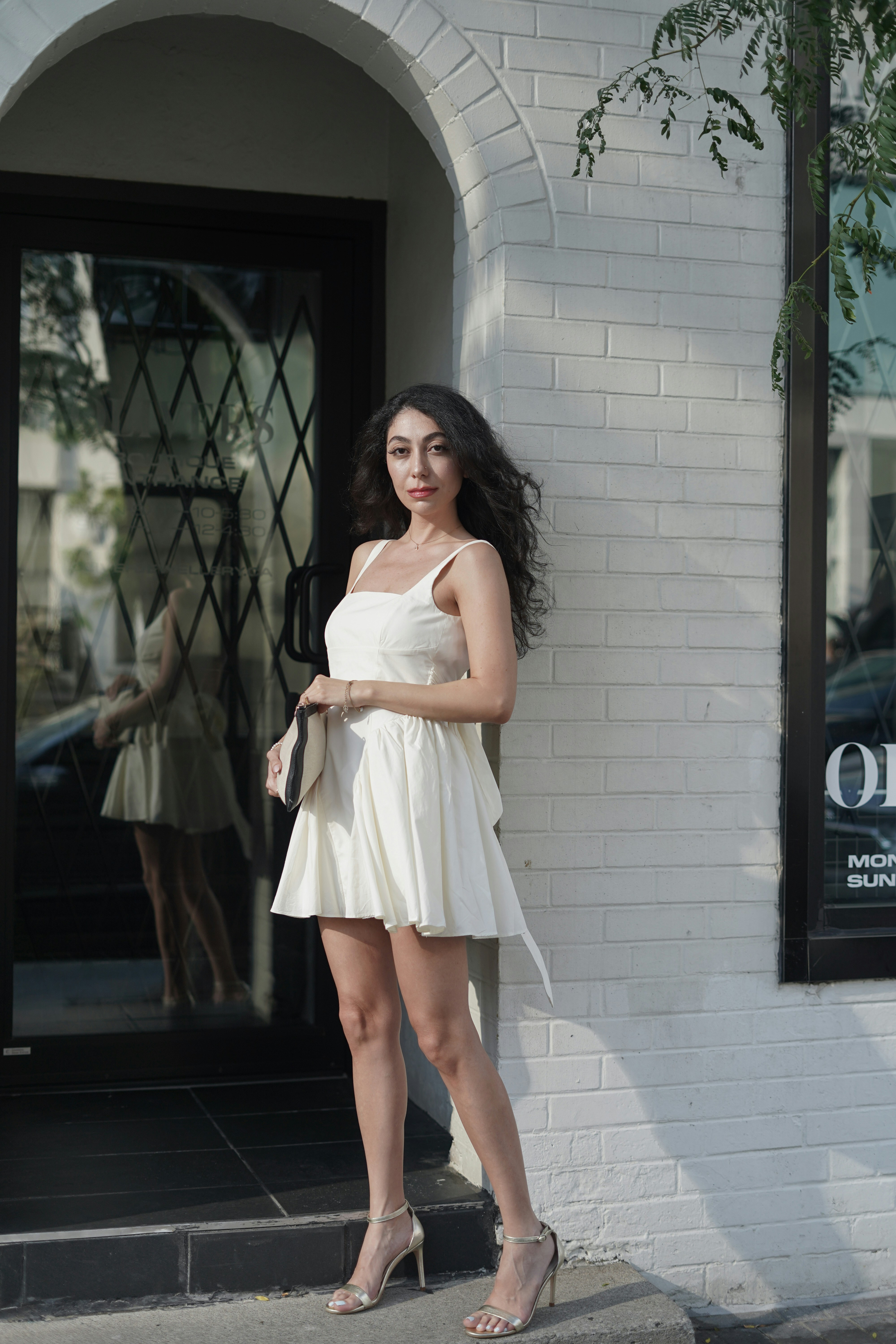 A woman in a short white dress standing in front of a building