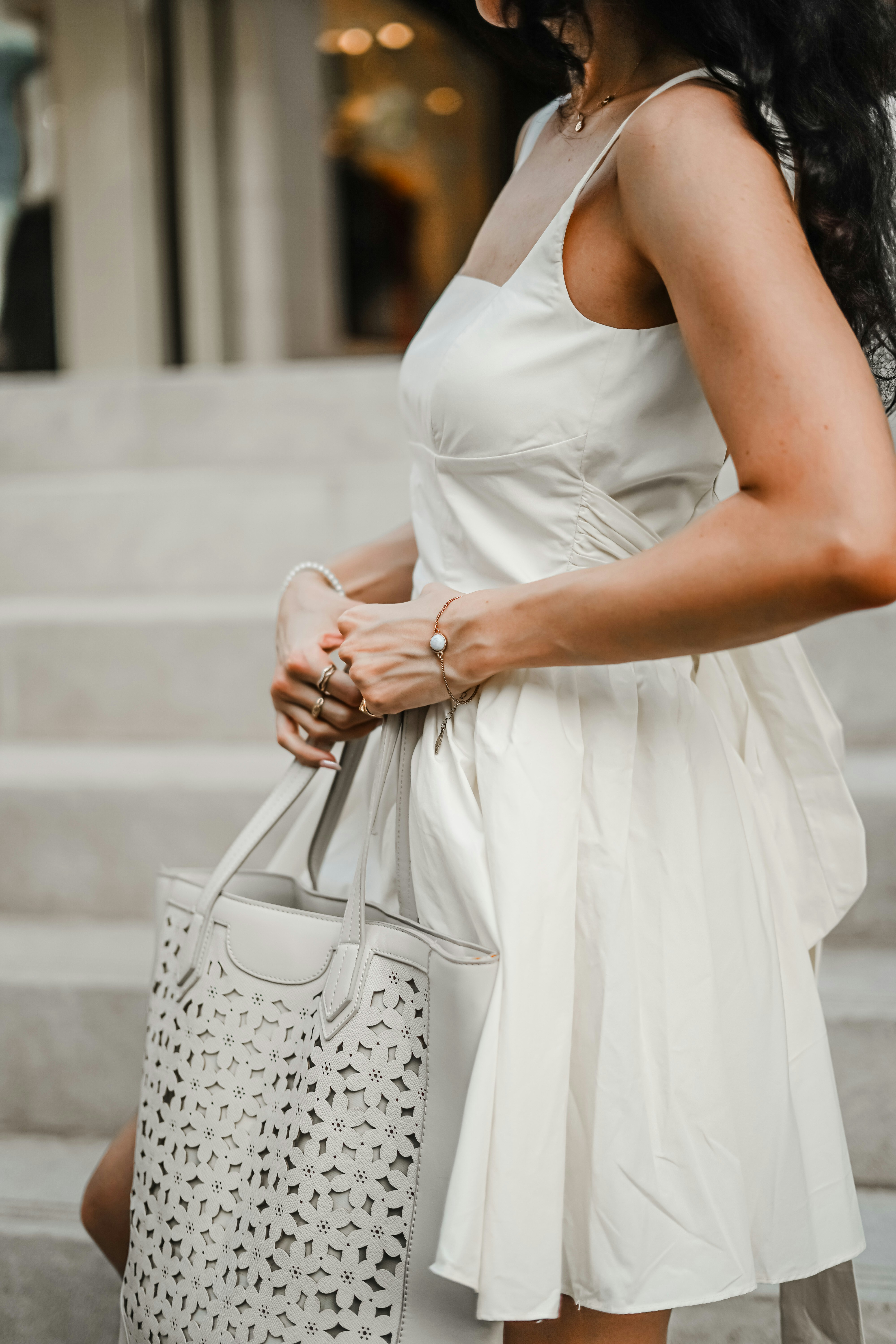A woman in a white dress carrying a white bag