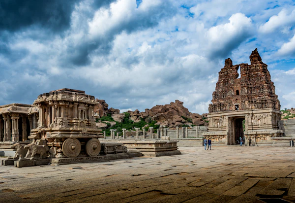 A group of ruined stone structures on open ground at Hampi