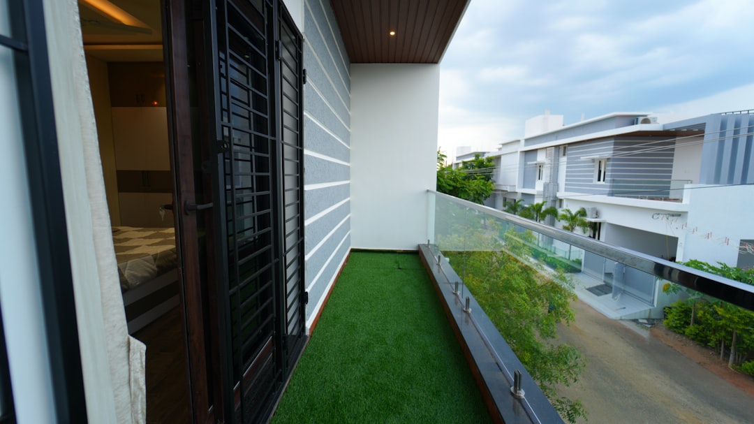 A balcony with a green lawn and a view of a building, Book your eco-friendly home today and enjoy a greener lifestyle at an affordable price. Experience comfort and conservation in every corner of your new home.