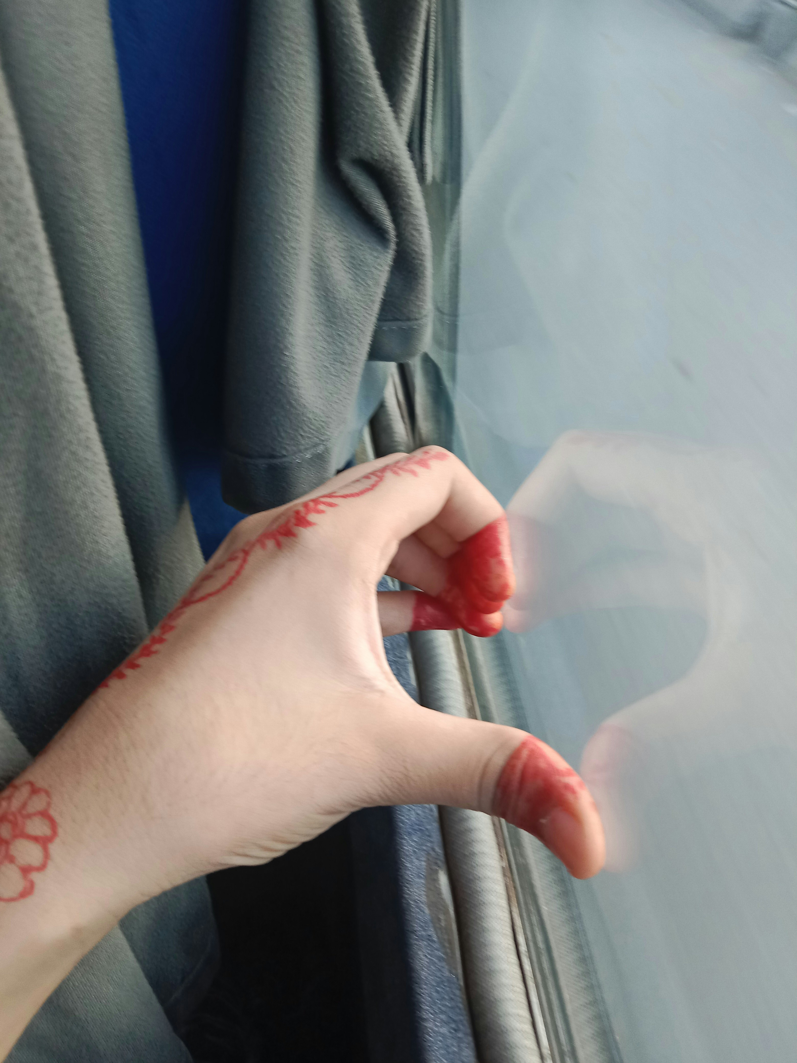 A person's hand with a red tattoo on their left hand
