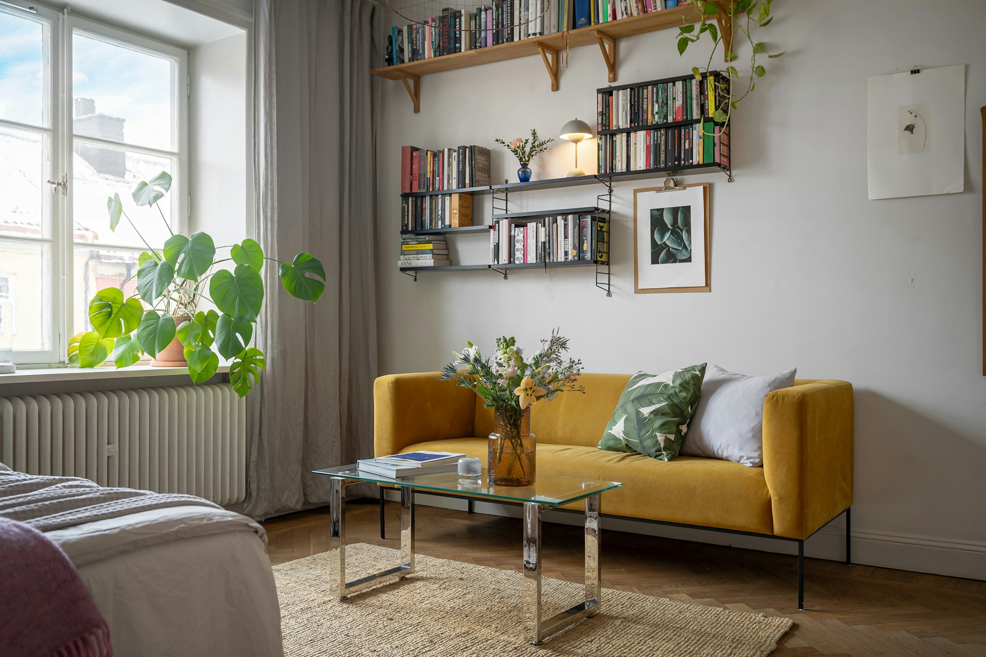 A living room with a yellow couch and bookshelf