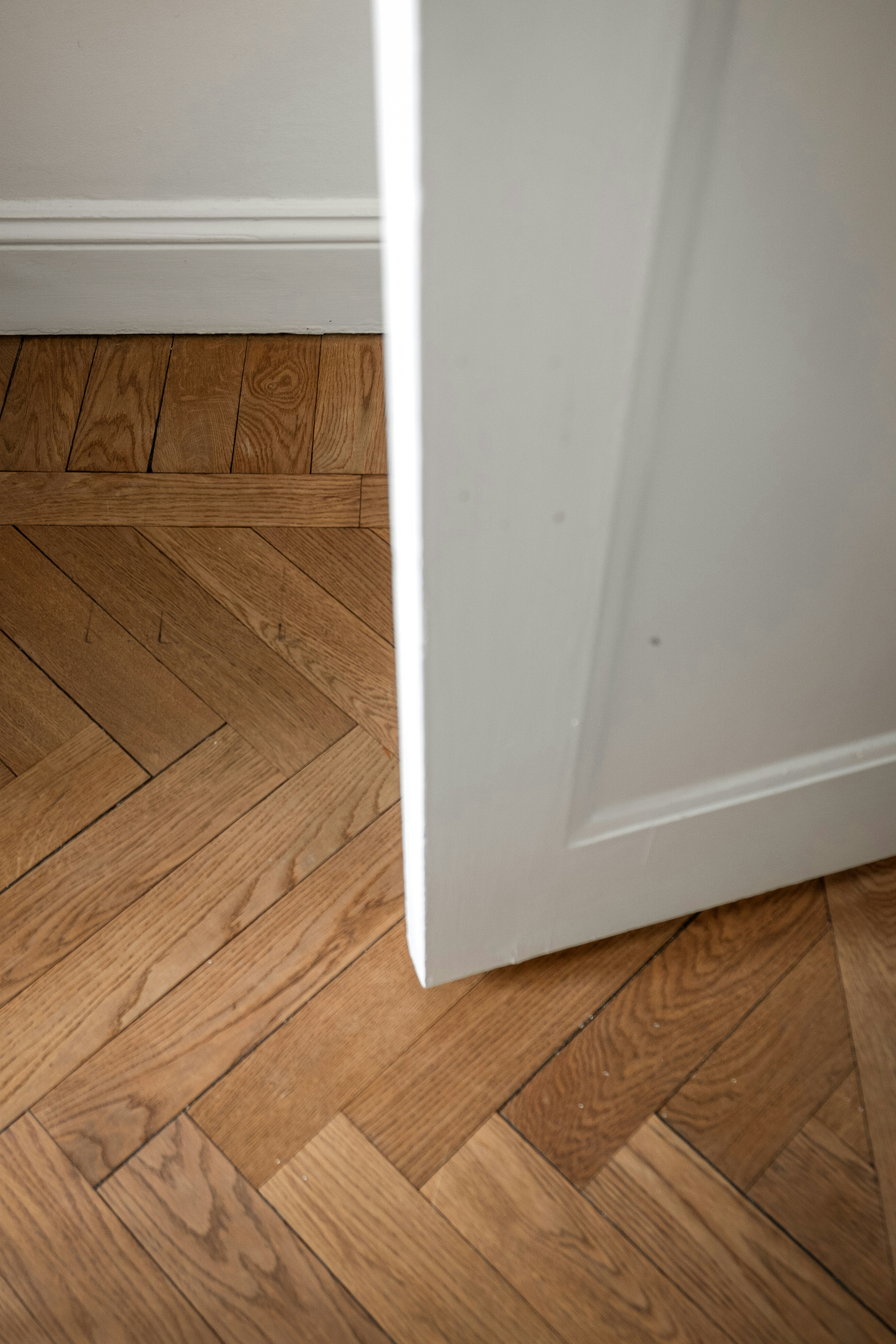 A white panelled door opening on to a herringbone oak floor