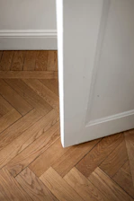 A white door is open on a wooden floor