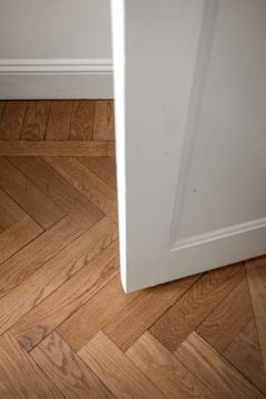 A white door is open on a wooden floor