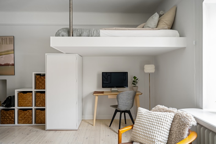 A room with a loft bed and a desk