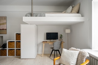 A room with a loft bed and a desk