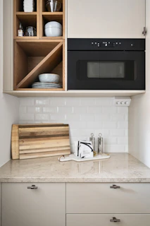 A kitchen with white cabinets and a black microwave