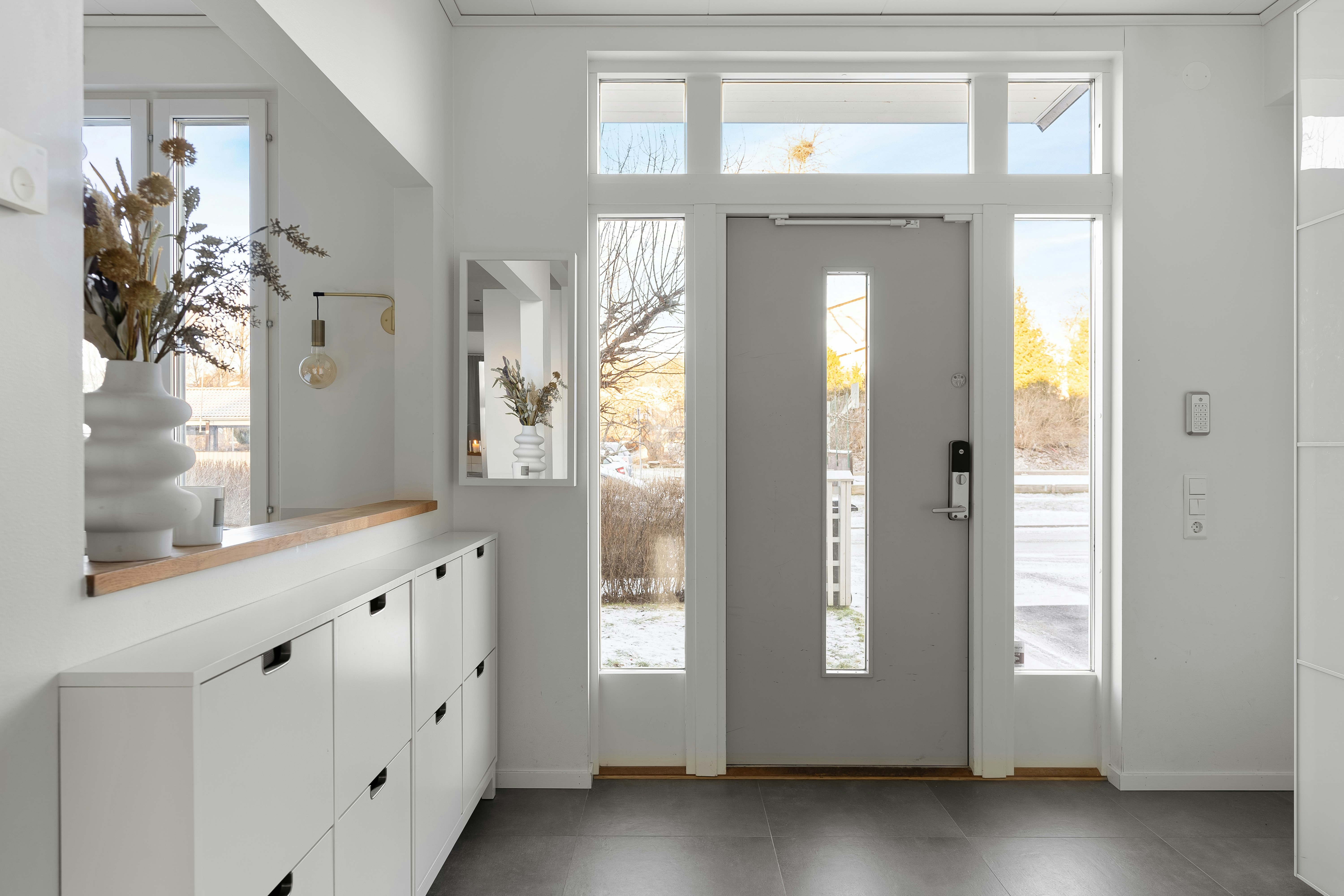 Bright home entryway with premium wood-grain fiberglass door, sidelights, and natural light flooding a welcoming foyer