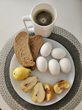 A white plate topped with sliced apples and a cup of coffee
