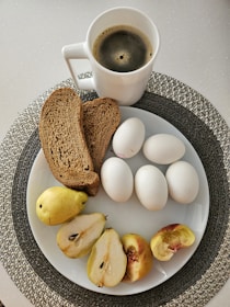 A white plate topped with sliced apples and a cup of coffee