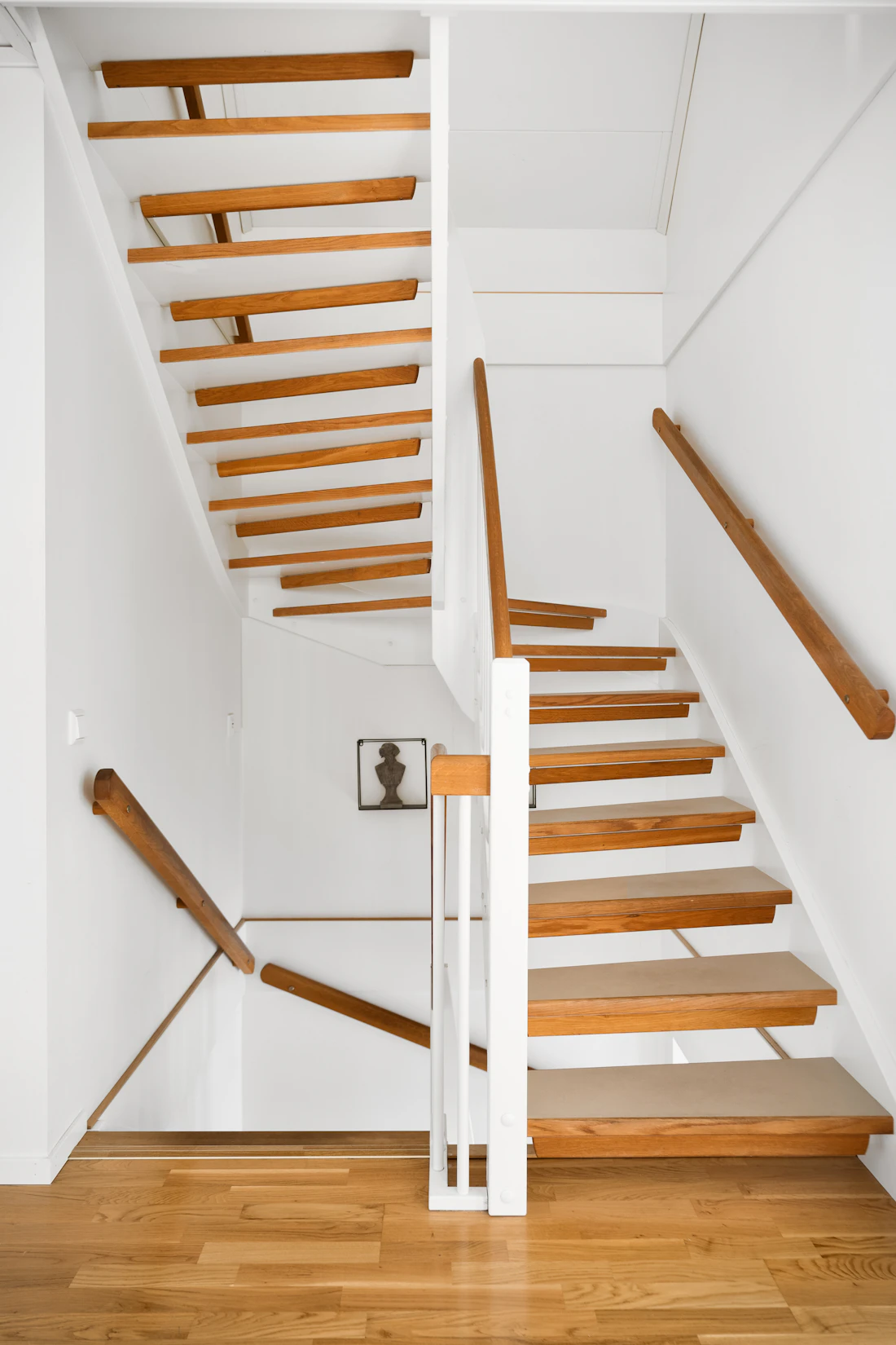 White residential staircase with warm wood handrails and wood stair treads