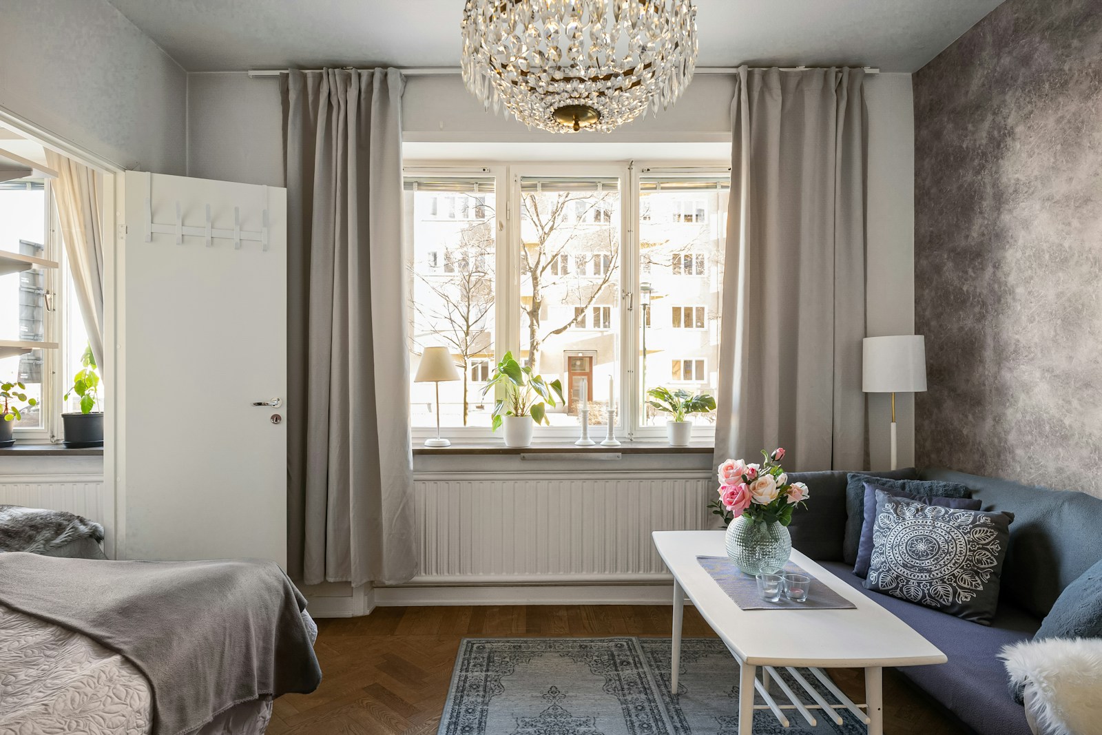 studio apartment with bed and living area zoned by curtains