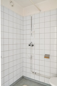 A white tiled bathroom with a shower and toilet