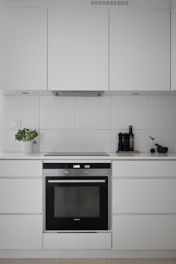 A kitchen with white cabinets and a black oven