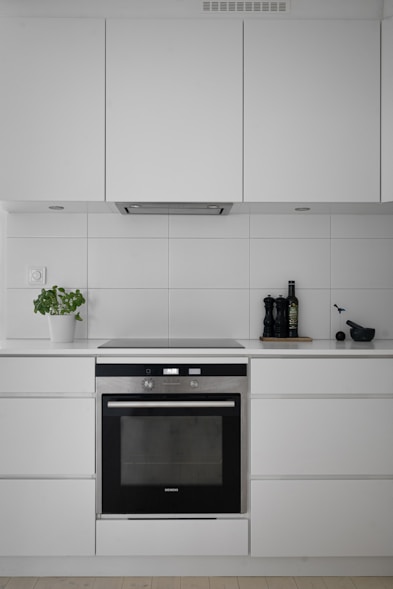 A kitchen with white cabinets and a black oven