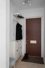 A white room with a brown door and white cabinets