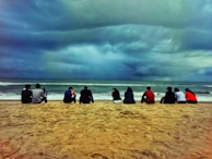 A group of people sitting on top of a sandy beach