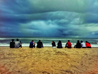 A group of people sitting on top of a sandy beach
