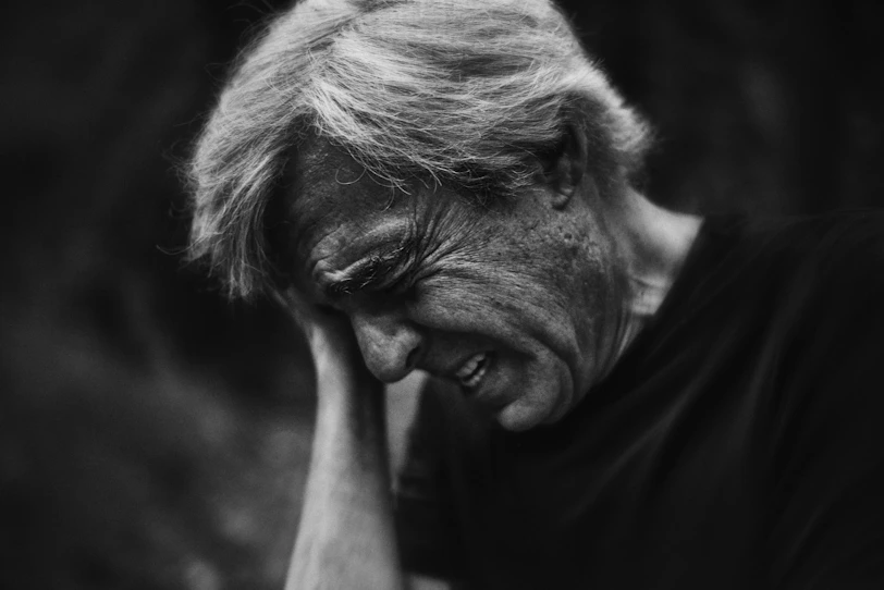 A black and white photo of a man with his hand on his face