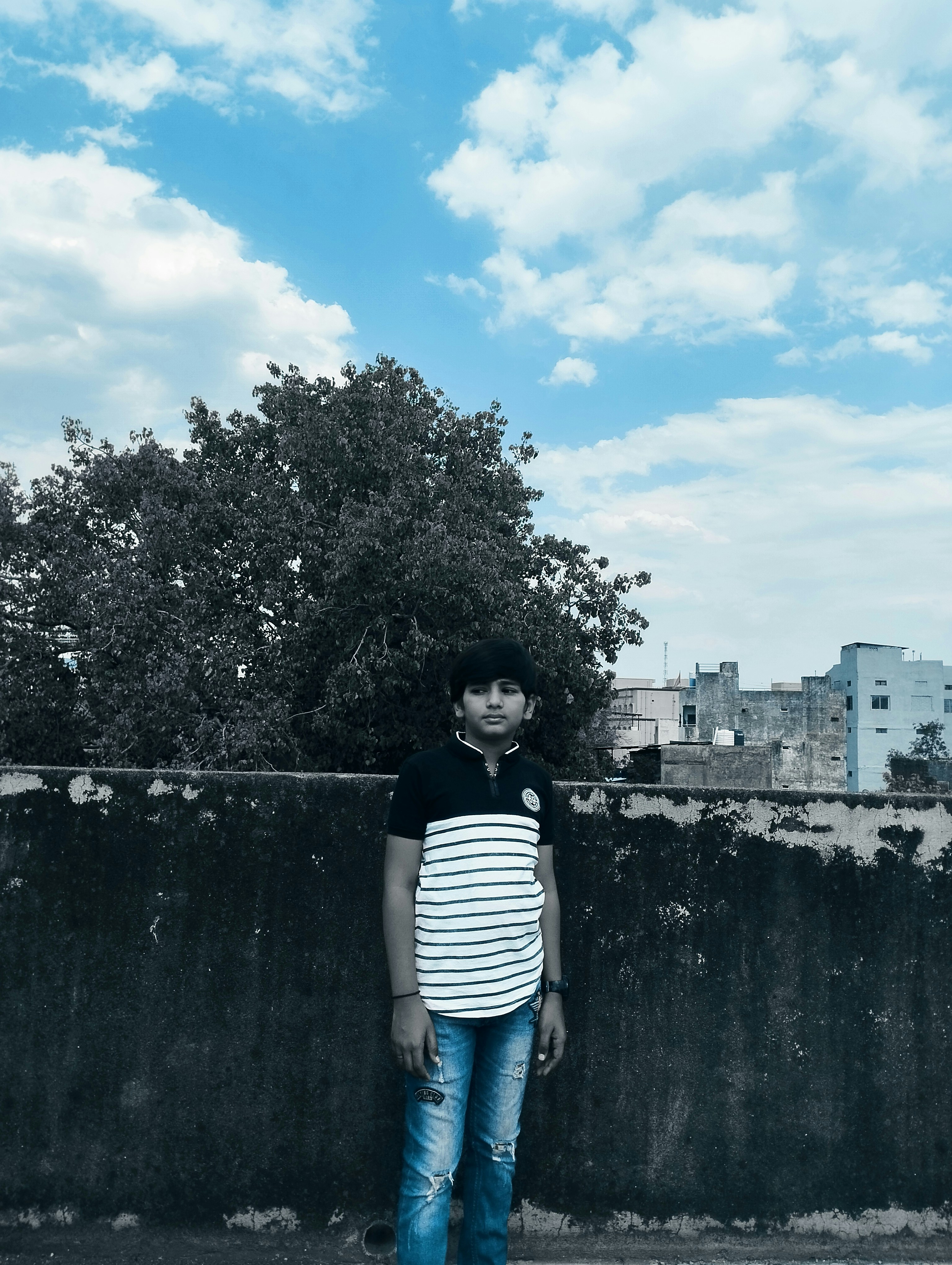 A young man standing in front of a fence