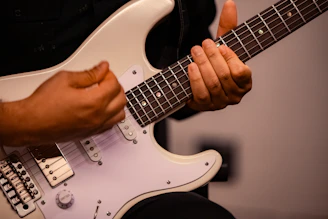 A person holding a white electric guitar