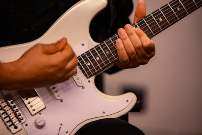 A person holding a white electric guitar