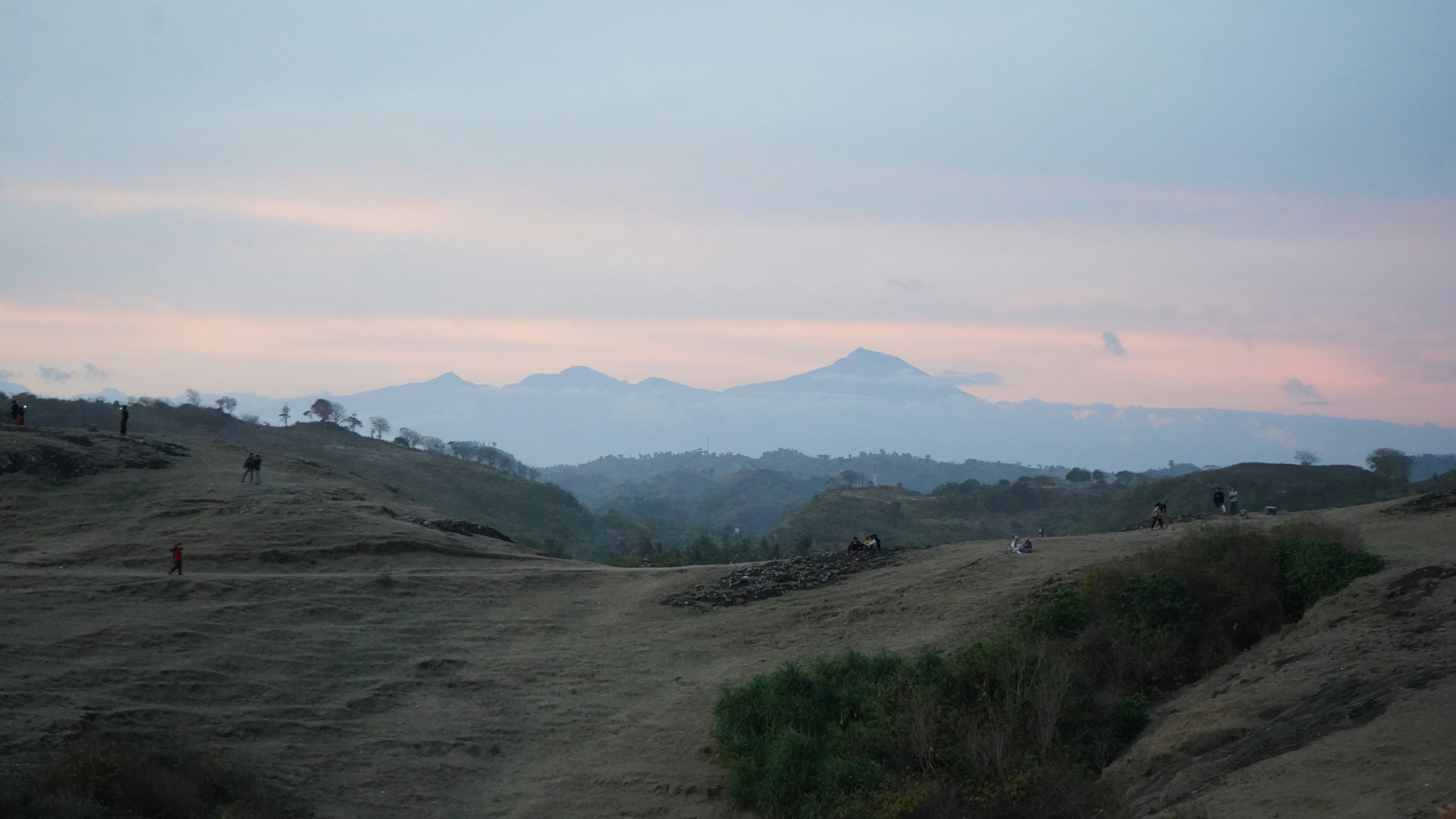 A view of a mountain range with a pink sky in the background