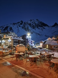 A snowy mountain town at night with tables and chairs