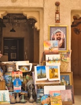A man standing next to a pile of paintings