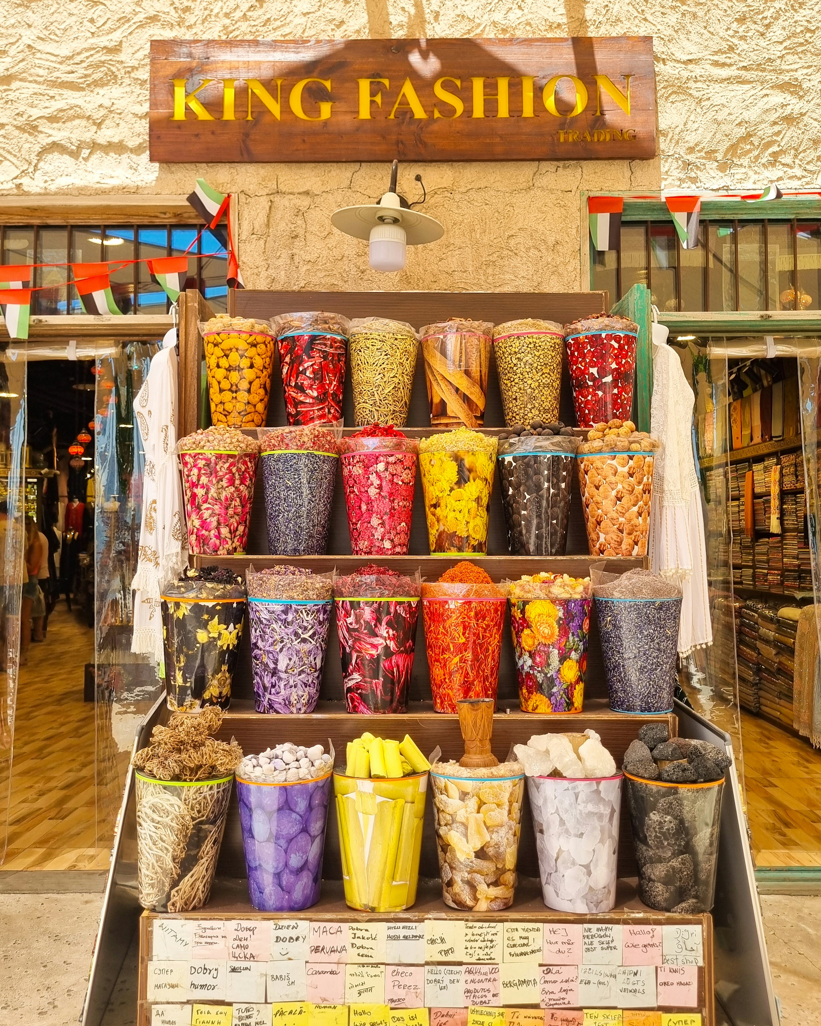 Colorful spices and herbs arranged on shelves outside a market store.