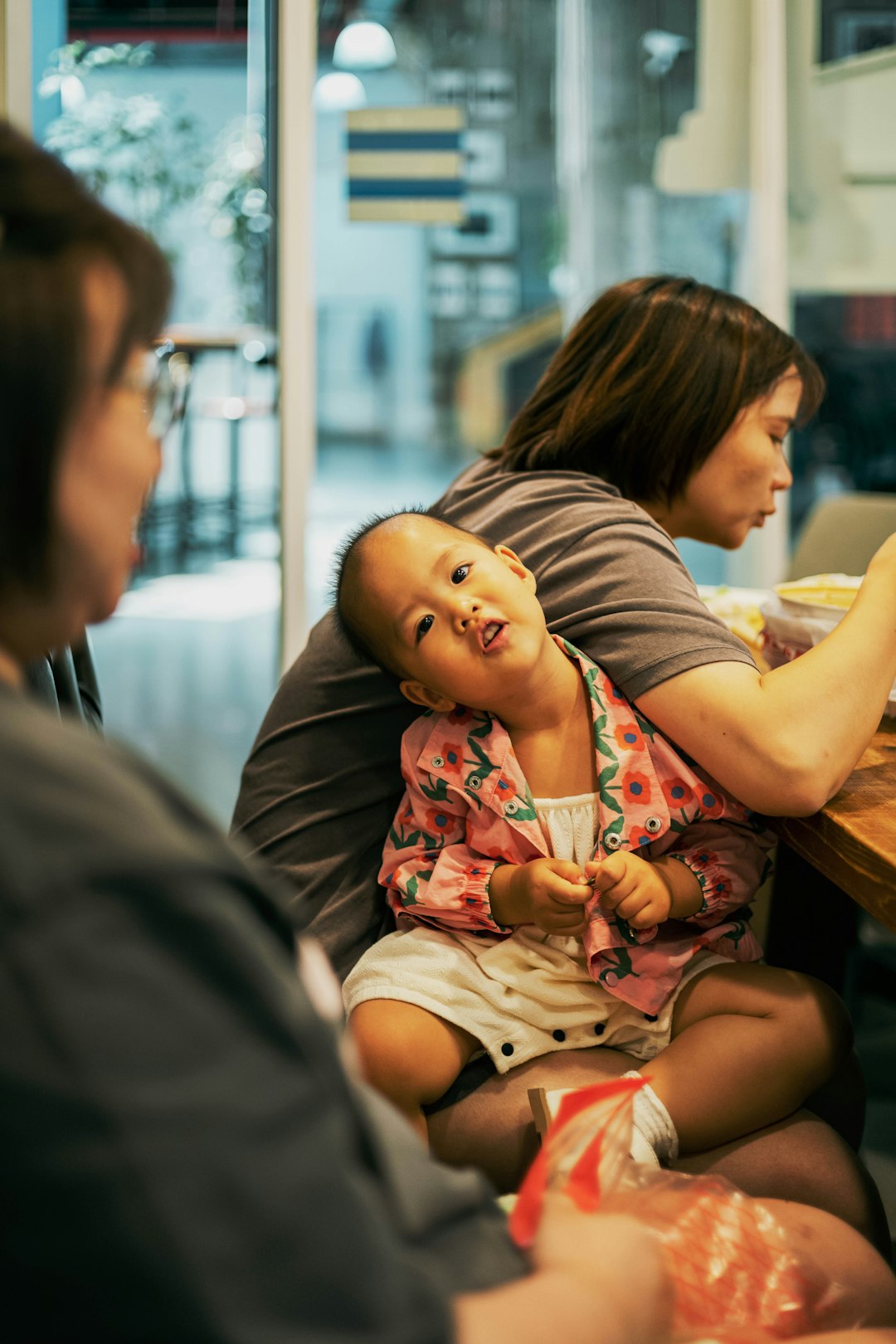 A woman sitting at a table with a baby in her lap