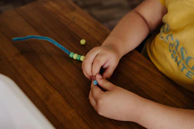 A child is playing with beads on a table