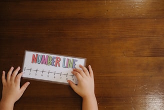 A child's hands on a wooden table with a calendar