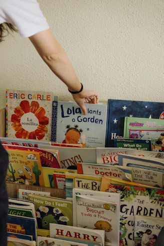 A person reaching for a book on a shelf