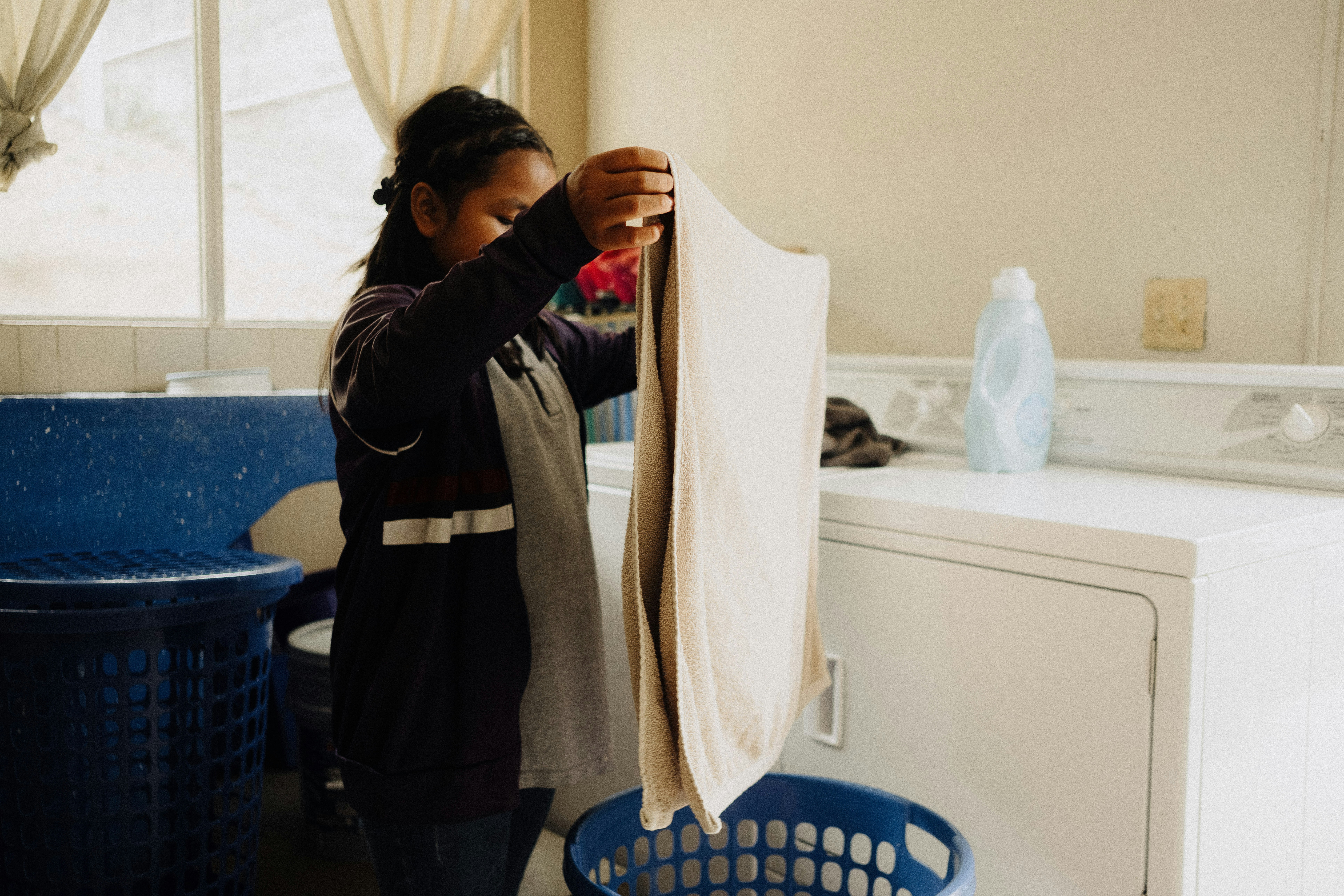 A woman standing in a kitchen next to a washing machine
