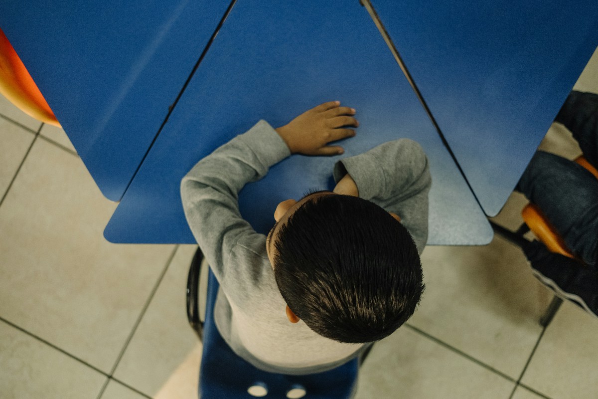 A young boy sits on a stool holding an umbrella, perfect for first day of school activities or classroom icebreakers.