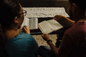 A man and a woman sitting on a bench reading a book
