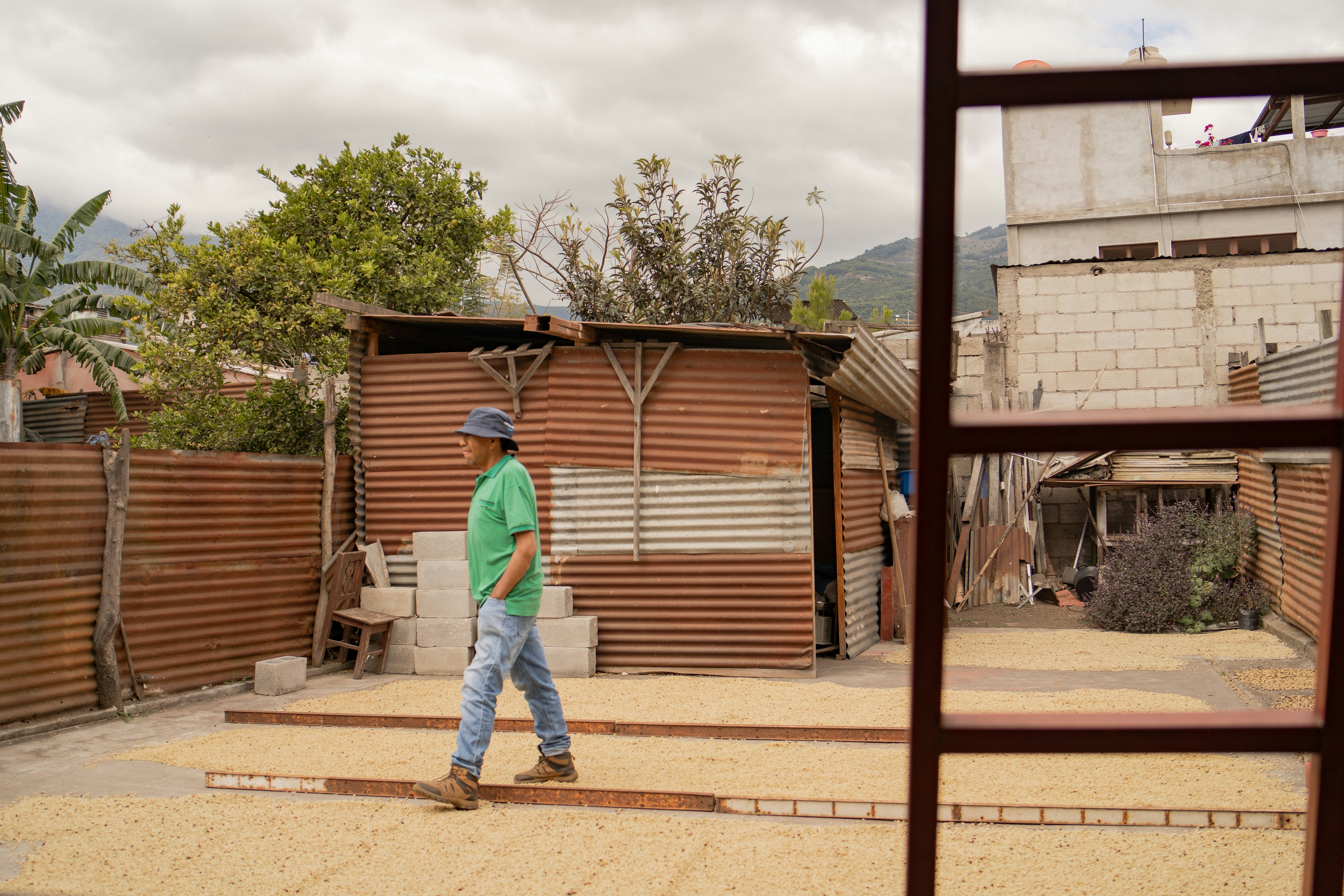 A man walking across a street next to a wooden fence
