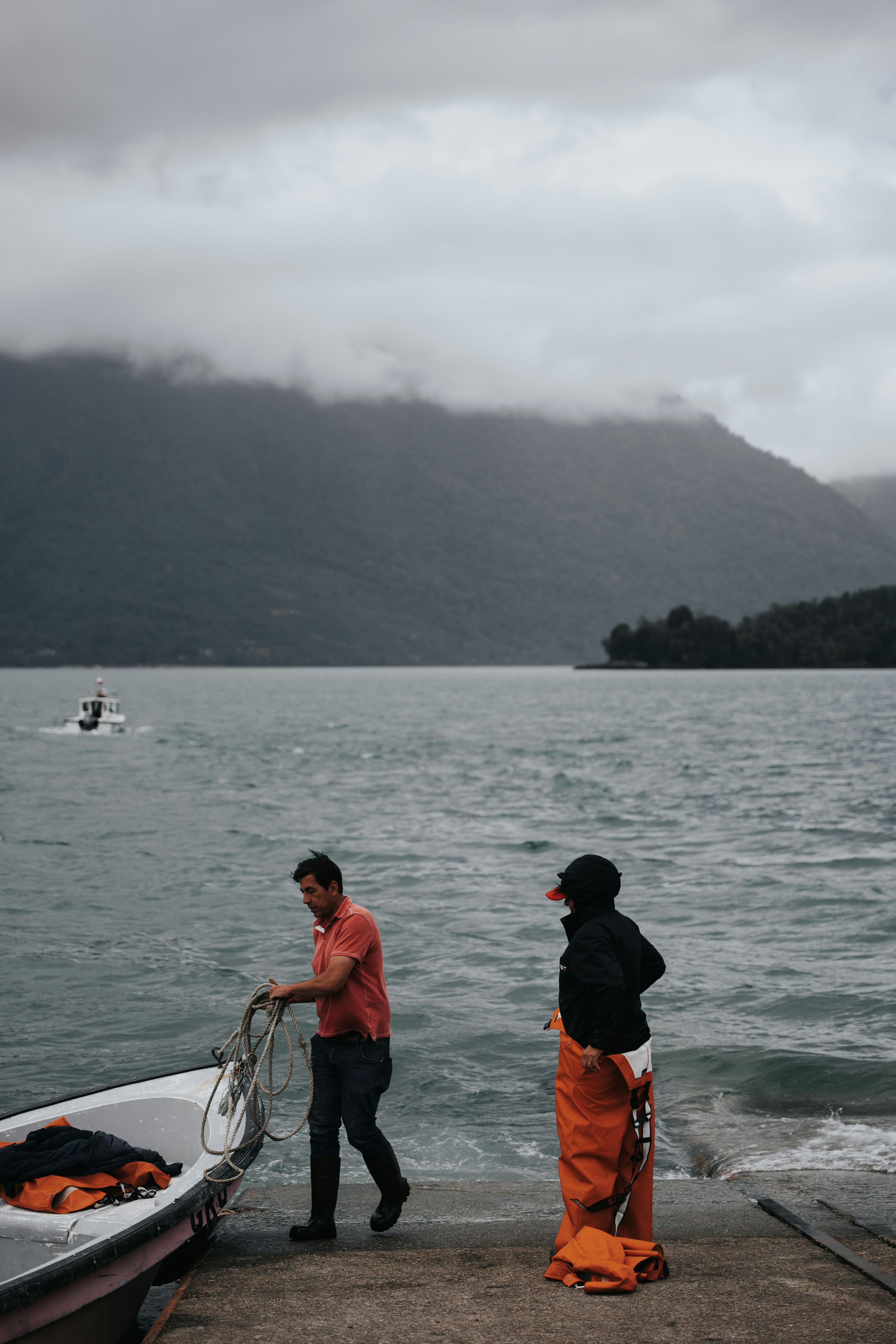 Un par de personas de pie junto a un barco en un cuerpo de agua