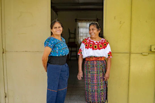 Two women standing next to each other in front of a building